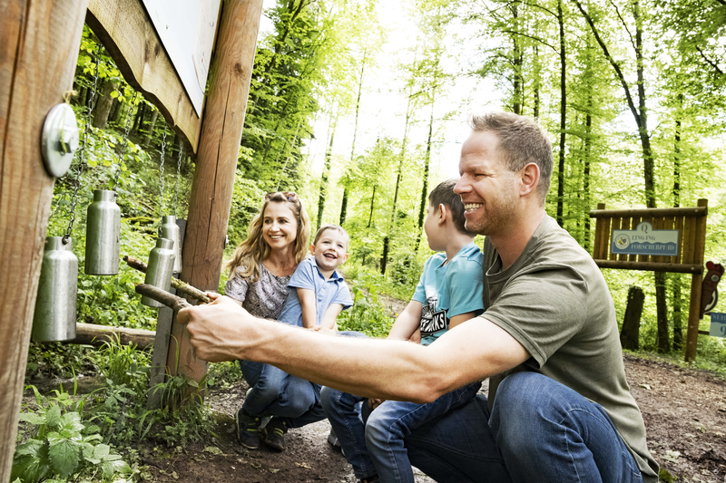 Familie spielt an Erlebnisstation mit Flaschen